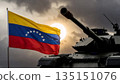 venezuelan flag and silhouette of a military tank against a bright setting sun and dark storm clouds 135151076