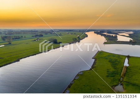Lowland river IJssel through sunset landscape Lowland river IJssel through sunset landscape 135151334