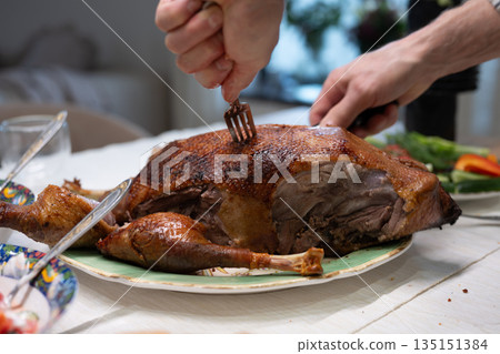 Chef carving roasted duck on serving platter for festive holiday meal Chef carving roasted duck on serving platter for festive holiday meal 135151384