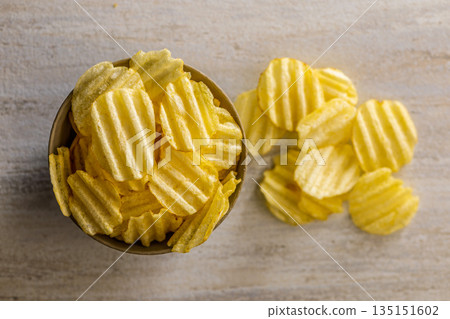 Wavy potato chips in bowl on kitchen table. Top view. 135151602