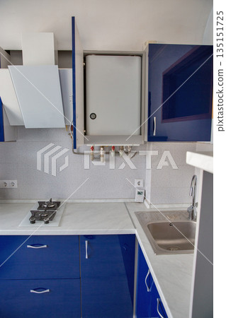 Modern kitchen with blue cabinets and dual gas boiler. 135151725