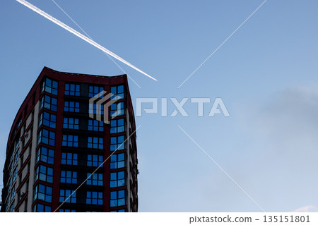 Sleek modern structure capturing gentle evening glow alongside flight path of aircraft Sleek modern structure capturing gentle evening glow alongside flight path of aircraft 135151801