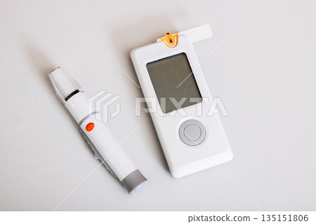 Minimalist medical scene showcasing glucose meter and lancet for health monitoring 135151806