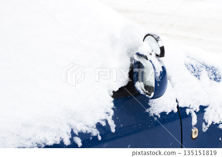 Vehicle buried beneath heavy snowfall with obscured features and vacant roadside environment 135151819