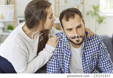 Sad man listens as partner whispers, theme of influence, manipulation, and control Sad man listens as partner whispers, theme of influence, manipulation, and control 135151837