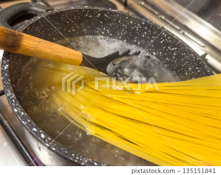 Pasta Cooking Scene, Homestyle Cooking Moment With Golden Noodles Simmering In Pot Of Hot Water 135151841