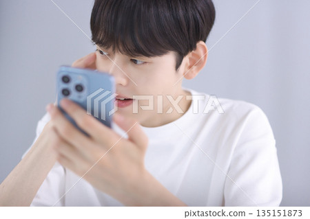 A young man looking at his smartphone in the living room and feeling disappointed 135151873