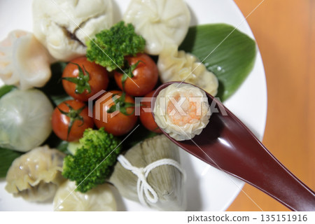 Dim sum and cherry tomatoes served overlooking the plate 135151916