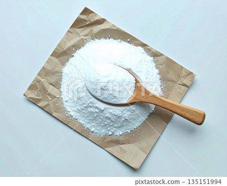 Eco cleaning blogs. Pile of powdered detergent with a wooden spoon on kraft paper on a white background. 135151994
