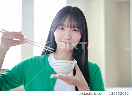 A young woman eating rice 135152012