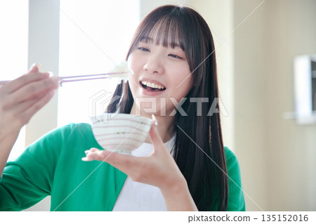 A young woman eating rice A young woman eating rice 135152016