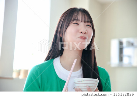 A young woman eating rice A young woman eating rice 135152059
