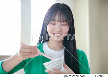 A young woman eating rice 135152063