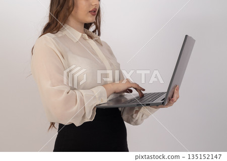 Businesswoman working on a laptop while standing. Businesswoman working on a laptop while standing. 135152147