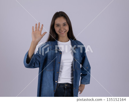 Happy young woman waving her hand in greeting. 135152164