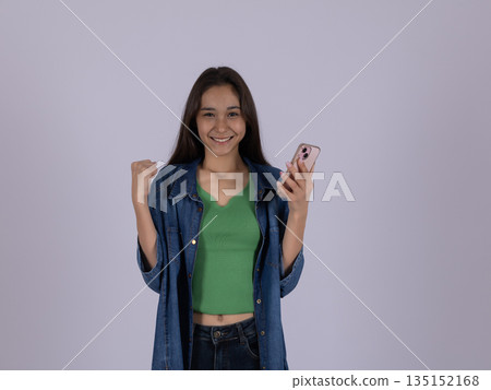 Happy woman in green top holding a smartphone. Happy woman in green top holding a smartphone. 135152168