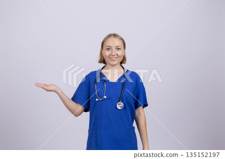 Female doctor in a blue uniform pointing to the side. 135152197