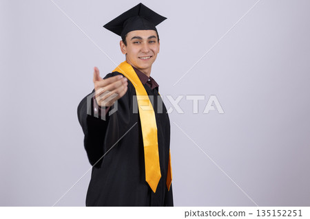Student in a graduation gown and cap waving hello. Student in a graduation gown and cap waving hello. 135152251