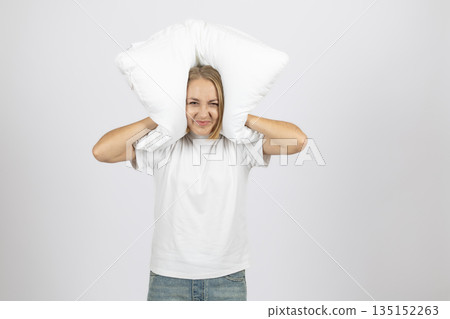 Woman holding a pillow behind her head and screaming. 135152263