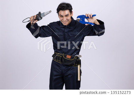 Electrician in overalls holding power tools above his head. 135152273