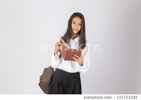 Teenager girl holding a notebook and looking thoughtful. Teenager girl holding a notebook and looking thoughtful. 135152292
