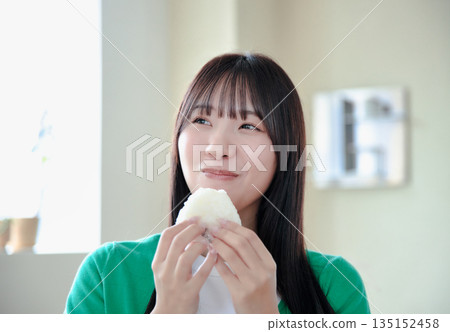 一位年輕女子津津有味地吃著飯糰。 一位年輕女子津津有味地吃著飯糰。 135152458