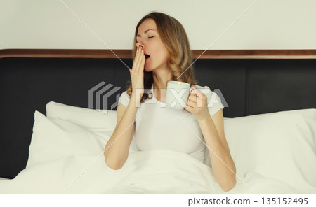 Sleepy lazy young woman yawns wakes up after sleep in the bed in morning at home Sleepy lazy young woman yawns wakes up after sleep in the bed in morning at home 135152495