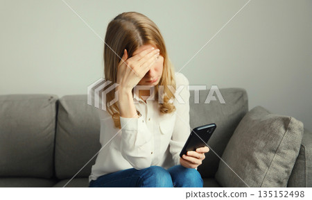 Sad upset crying woman holding phone suffering from stress after reading emotional message at home Sad upset crying woman holding phone suffering from stress after reading emotional message at home 135152498