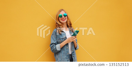 Summer happy young woman with phone, modern smiling girl holding smartphone on yellow background 135152513