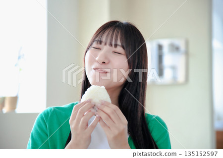 A young woman eating rice balls with relish 135152597