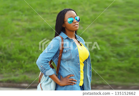 Portrait of stylish young African woman student with backpack, black girl outdoors in summer park 135152662