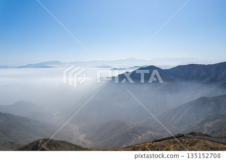 The sky is blue and the mountains are covered in fog The sky is blue and the mountains are covered in fog 135152708