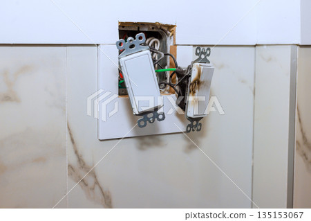Two damaged light switches are seen on wall during home renovation process Two damaged light switches are seen on wall during home renovation process 135153067