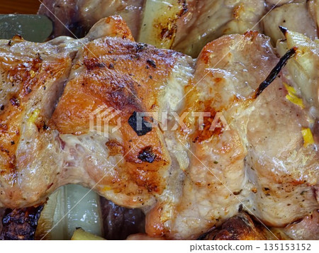 Close-up of the grilled pork with onions on skewers. Family dinner al fresco. 135153152