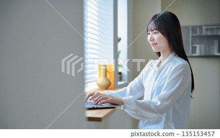 A woman in her twenties operating a laptop A woman in her twenties operating a laptop 135153457