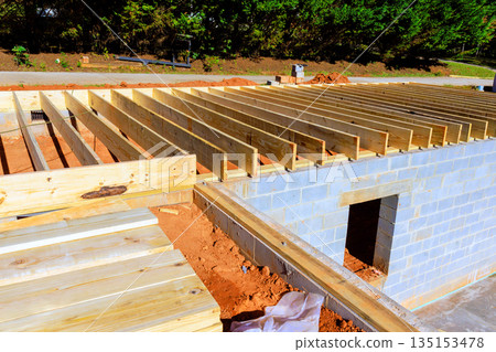 Workers are building wooden frame trusses on concrete structure with tools materials at construction site. 135153478
