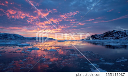 Vibrant sunset reflecting on icy waters with colorful clouds over distant mountains 135155087