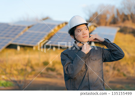 A worker standing in front of a solar panel 135155499