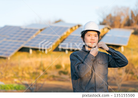 A worker standing in front of a solar panel 135155500