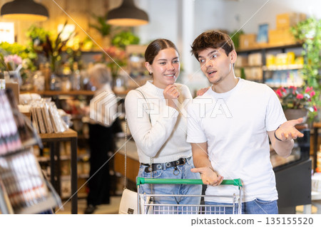 Couple man and woman with shopping cart choosing products Couple man and woman with shopping cart choosing products 135155520