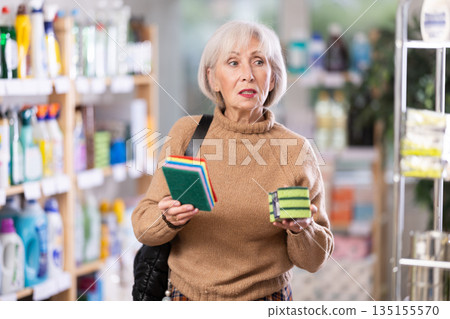 Mature woman choosing cleaning sponge in department store Mature woman choosing cleaning sponge in department store 135155570