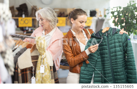 woman, together with a mature woman, chooses outerwear woman, together with a mature woman, chooses outerwear 135155605