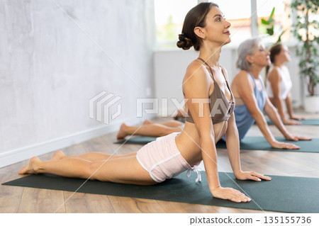 Young woman doing yoga in group in studio Young woman doing yoga in group in studio 135155736