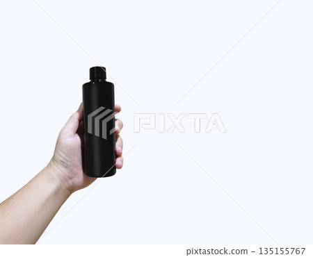 A hand holding a black plastic bottle against a white background. 135155767