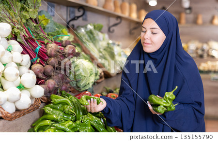 Delighted young Muslim woman purchaser choosing pepper in grocery store Delighted young Muslim woman purchaser choosing pepper in grocery store 135155790