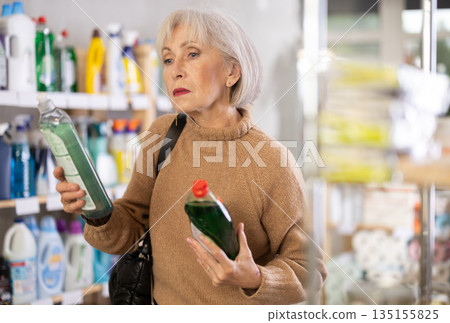 Elderly female customer diligently picking out dishwashing liquid 135155825