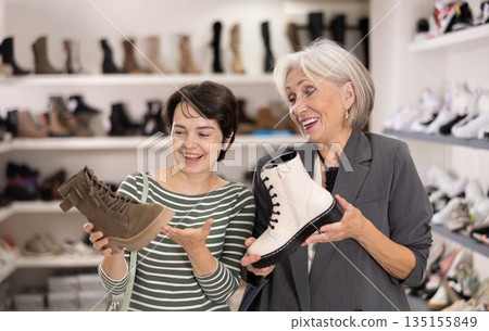 Adult and elderly women choosing boots in store 135155849