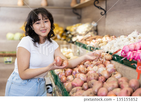 Portrait of female customer selecting onion in grocery 135155852