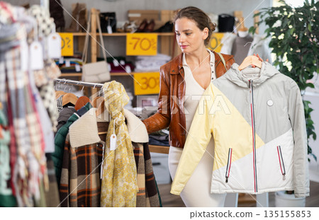 Young woman choosing down jacket in clothing store Young woman choosing down jacket in clothing store 135155853