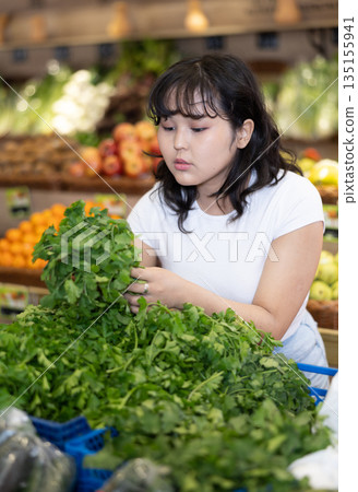 Young asian girl hoosing fresh greens in farm store 135155941